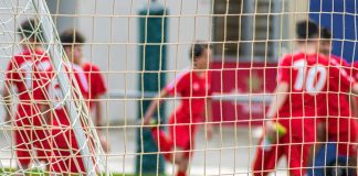 soccer players in red jersey shirt playing soccer during daytime