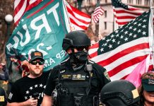 man in black police uniform holding us a flag