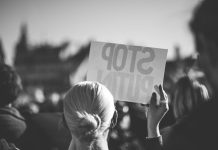 a woman holding a sign that reads stop pluto