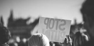 a woman holding a sign that reads stop pluto