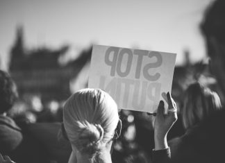 a woman holding a sign that reads stop pluto