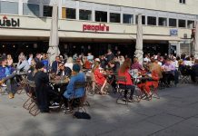 People in Oslo Flock to Restaurants and Coffees, Forget Social Distancing With Lockdown Easing A group of people sitting at a bar outside.